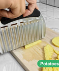 Close-up of stainless steel crinkle cutter with black handle slicing potatoes on a wooden board