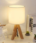 Cozy Kids Table Lamp With Fabric Shade And Wood Tripod Base on desk, warm glow lighting a kid's room or dorm, compact modern style