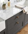 Heavy Duty 15 Piece Antique Brass Cabinet Knobs Offering A Hella Smooth Vintage Sunburst Finish on kitchen drawer with marble countertop.