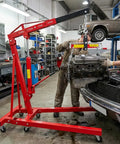 Heavy Duty Folding Hydraulic Engine Hoist With 4400 Lbs Capacity Cherry Picker Crane lifting a car engine in a garage.