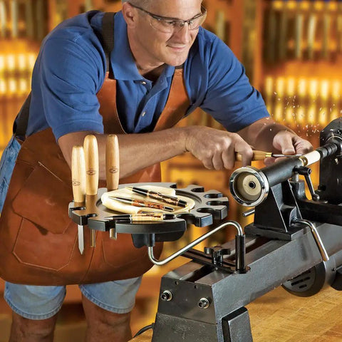 Woodworker using Heavy Duty Lathe Tool Holder With Steel Pivot Arm And 12 Slot Tray For Woodturning Chisels, mounted on lathe bed.