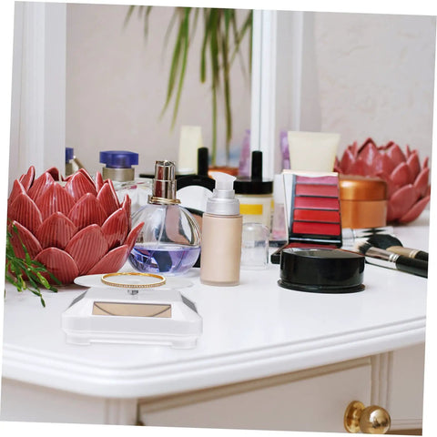 Solar Powered Rotating Display Turntable For Jewelry Phones And Accessories Lightweight Compact Electric Showcase Stand With Good Load Capacity Perfect For Exhibition Displays And Retail Shops displaying jewelry and beauty products on a vanity.