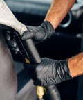Schneider black vinyl exam gloves, 4mil, latex-free, medium, gripping a metal tool.