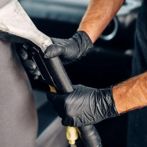 Schneider black vinyl exam gloves, 4mil, latex-free, medium, gripping a metal tool.