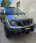 Premium Steel Ditch Light Brackets For 2005-2017 Nissan Xterra And Frontier mounted on a gray Nissan with LED lights.