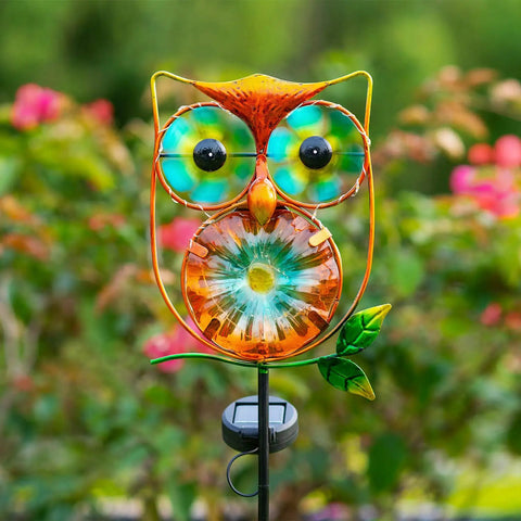 Solar Powered Owl Wind Spinner Stake Light for Outdoors With Warm White LEDs, copper owl with vibrant eyes in garden setting.