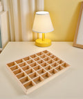Top Tier Solid Wood Jewelry Tray Organizer Designed To Keep Your Bling Neatly Arranged In 36 Grids On a table with lamp.