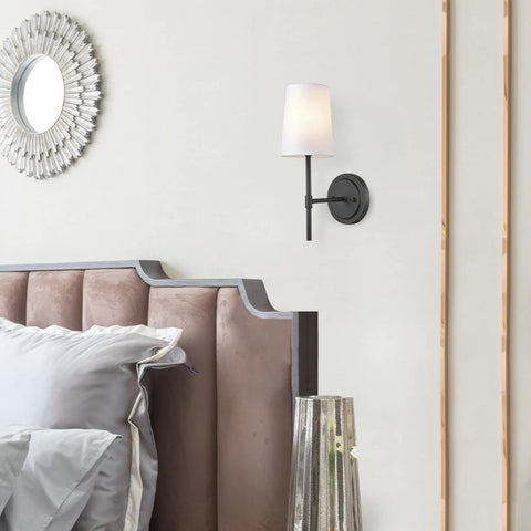 Matte Black 1-Light Wall Sconce With White Fabric Shade in a bedroom setting, mounted above a headboard.
