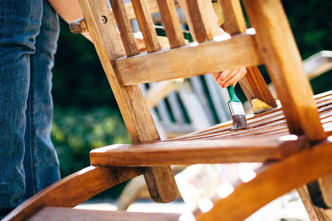 Applying Premium Clear Wood Stain With Semi Gloss Finish on a wooden chair slat outdoor, preserving its natural grain.