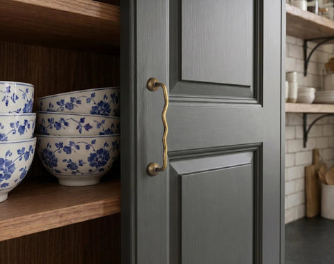 Solid Brass Cabinet Pulls With 5 Inch Hole Centers on gray kitchen cabinet showcasing ergonomic wave design and antique brass finish.