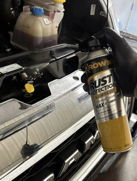 Person applying T40 Beefed Up Rust Protection And Lubricant to metal car engine bay, 14 oz can