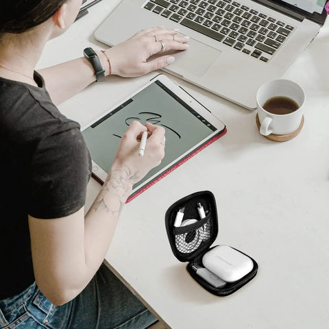 Carry Anywhere EVA Earbud Case With Carabiner on desk beside person using tablet, slim gear pouch open showing space for earphones and USB drives
