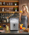 Woman enjoying drink beside Nugget Ice Maker Countertop With Fast 8 Minute Ice, Soft Chewable Sonic Ice, 35 Lbs Per Day, Self Cleaning and Quiet Operation, Compact Stainless Steel Design With Handy Carry Handle, Great For Home Bars And Office Break Rooms.