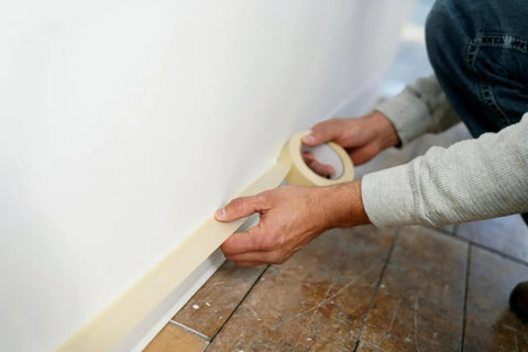 Person applying Economy Masking Tape Three Quarters Inch By Sixty Yards General Purpose Crepe Paper Backing on floor edge for sealing