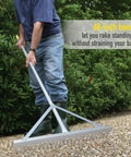 Person using landscape rake with aluminum head and 68 inch handle, 24 inch width with 24 tines, smoothing gravel on driveway