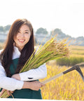 Woman in field holding a sickle with wooden handle grip. Wooden Sickle Handle Grip With Ergonomic Design And Noslip Comfort For Sickle Replacement.