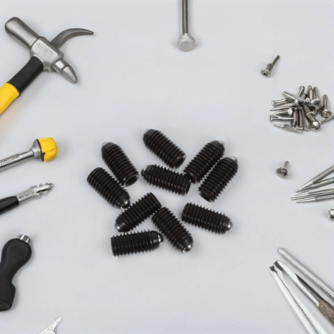 10 Piece Heavy Duty Carbon Steel Set Screws With Spring Loaded Ball Gripper Ends For Rock Solid Clamping displayed with tools on a workspace.