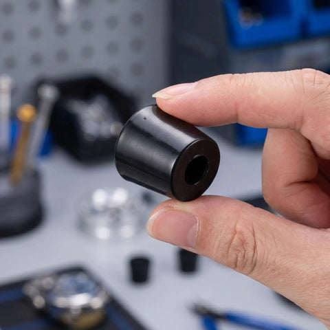 Close-up of a hand holding a Heavy Duty Black Rubber Door Stopper for Wall Mounted Installations, Set of 10.