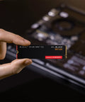 Person holding SN7100 1TB NVMe SSD Gen4 PCIe M2 2280 Up To 7250 MBps Read Speed And 6900 MBps Write Speed for laptops
