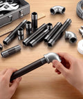 Hands assembling 66 Piece Half Inch Black Metal Pipe Nipples Set With 11 Size Assortment on a workbench with tools.