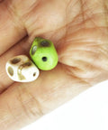 Close-up of two mixed color turquoise skull head spacer beads for DIY jewelry making on a hand, part of a pack of 50, tiny skull shape.