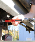 LockNLube Grease Buster red handheld tool being used to flush grease from a vehicle joint
