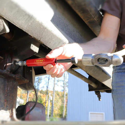 LockNLube Grease Buster red handheld tool being used to flush grease from a vehicle joint