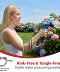 A woman using a 100 Ft Stainless Steel Garden Hose No Kinks And Leak Proof Flexible Water Hose with nozzle in a flower garden.