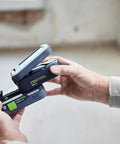 Person holding Go Anywhere Cordless Task Light SYSLITE KAL C Go-To Handy Work Light in hands, showing battery insertion.