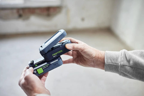 Person holding Go Anywhere Cordless Task Light SYSLITE KAL C Go-To Handy Work Light in hands, showing battery insertion.