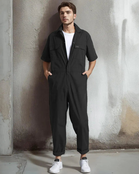 Lightweight Mens Short Sleeve Coveralls And Mechanic Work Jumpsuit Featuring Deep Cargo Pockets Woven From Breezy Summer Twill Cotton Blend For Tough Job Sites And The Daily Grind Low Key Comfy Shop Romper displayed on a model against a textured wall.