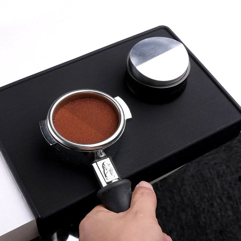 Barista using 58mm Coffee Distribution Tool for Portafilter Leveler with stainless steel base on black mat
