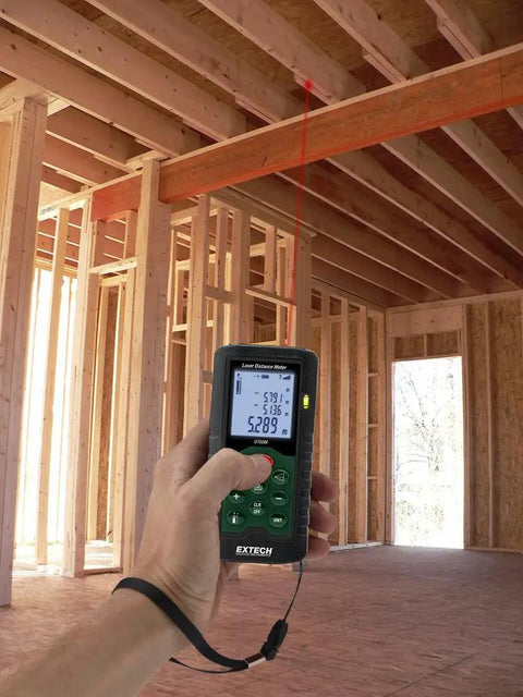 Hand using Laser Distance Meter 196 Feet Or 60 Meters Digital Laser Measure with backlit display in construction site.