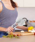 Woman using stainless steel frying tongs in kitchen setting