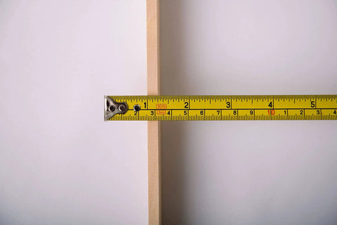 Close-up of a 21-inch American-Made Basswood Paint Stir Stick with a measuring tape showing its width for 5-gallon buckets.