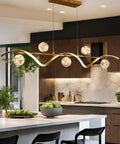 Modern Linear Pendant Light Set Featuring Six Glass Globe Shades Dimmable Gold Kitchen Island Fixture over sleek countertop.