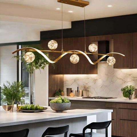 Modern Linear Pendant Light Set Featuring Six Glass Globe Shades Dimmable Gold Kitchen Island Fixture over sleek countertop.