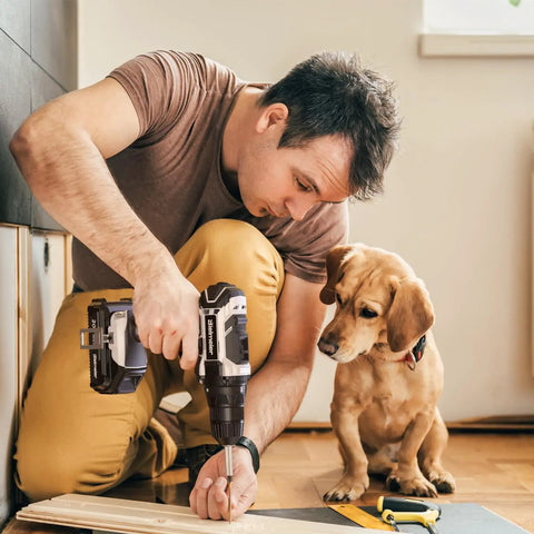 Man using 20V Cordless Drill Kit With 100 PC Drill Bit Set And 3 Eighths Inch Keyless Chuck LED Light, dog watching