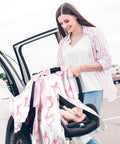 Woman using Pink Bow 2-In-1 Muslin Baby Car Seat Cover Breathable Nursing Shield For Breastfeeding on a car seat.