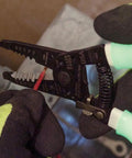 Glow In The Dark Grips Wire Stripper And Cutter With Serrated Curve Nose For 10 To 18 AWG Solid And 12 To 20 AWG Stranded Wire Pro Grade Tool Made In USA, showing wire stripping in progress