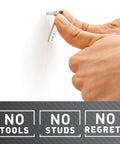 Hand installing Heavy Duty Drywall Picture Hangers Six Pack Holds Up To 15 Lbs Each With No Studs Required for easy wall mounting.
