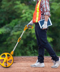 Man using Pro Grade Measuring Wheel With Easy Brake At The Handle And One Touch Zero Reset No Fuss on a construction site