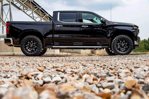 Side view of Chevy GMC 1500 on gravel with 2 Inch Red Aluminum Leveling Kit For Chevy And GMC 1500 2007 To 2018 Level Front To Rear