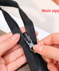 Close-up of black resin zipper with hand adjusting slider, part of Zipper Repair Kit Six Piece Set With Three Slider Sizes 3 5 And 8