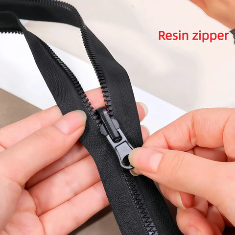 Close-up of black resin zipper with hand adjusting slider, part of Zipper Repair Kit Six Piece Set With Three Slider Sizes 3 5 And 8