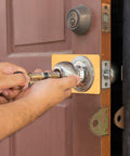 Hands installing Two Pack Stainless Steel Door Lock Reinforcement Plates With Adhesive Tape Gold Finish on wooden door.