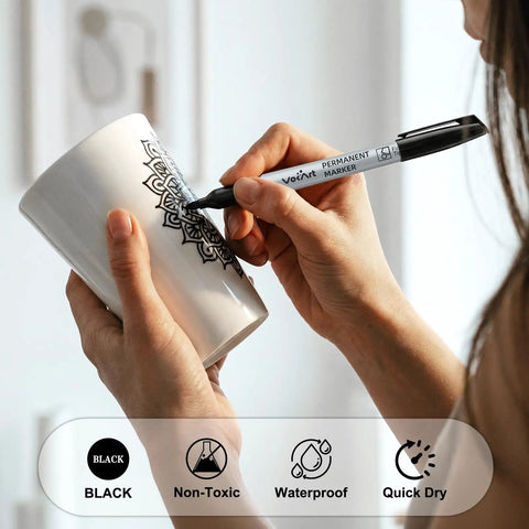 Person using Bulk Black Permanent Markers 150 Pack With Fine Point Tips For Office And Moving, Quick Dry Waterproof Ink Pens on a mug