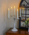 Six Pack 7.5 Inch Ivory Flameless LED Taper Candles with Remote on a vintage candelabra near a window