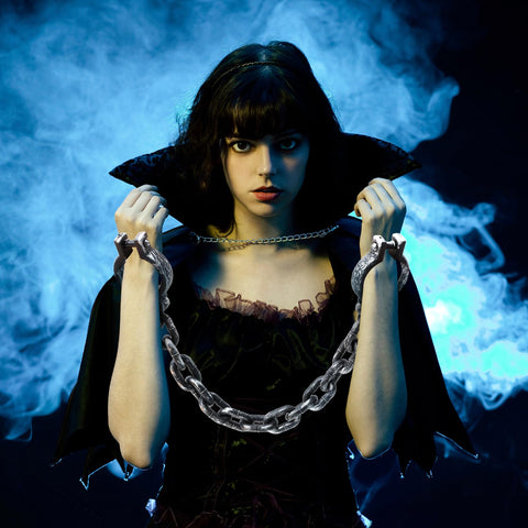 Woman with Halloween Plastic Wrist Shackles Handcuffs With Chain Links For Cosplay And Party Decor, Realistic Black 35 Inch Prop Accessory in spooky backdrop