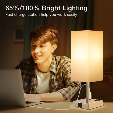 Person working by Set Of Two Touch Nightstand Lamps With USB C And USB A Ports AC Outlets Three Way Dimmable Bedside Lamps With White Fabric Shade Perfect For Bedroom Or Guest Room Bulb Included, featuring USB cable connected to a laptop.